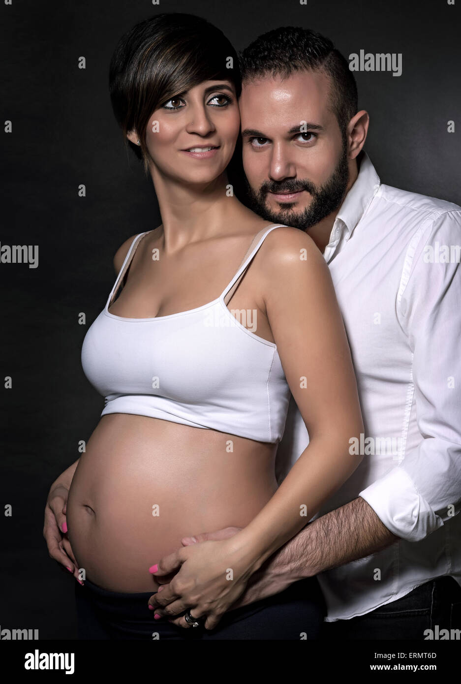 Ritratto di carino coppia felice aspetta baby su sfondo nero, godendo la gravidanza e ogni altro amore e felicità Foto Stock