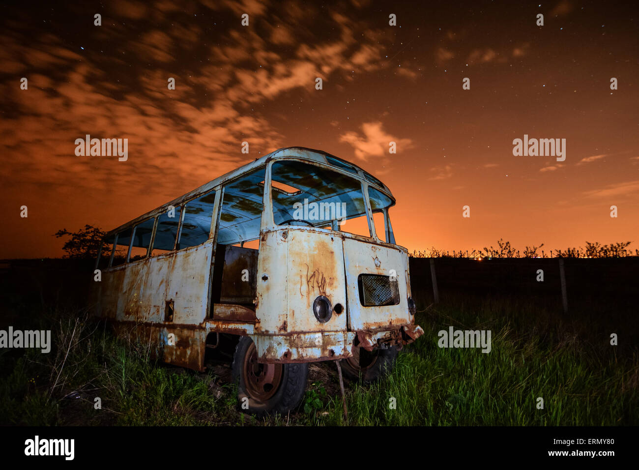 Vecchio autobus arrugginito in luce insolita di notte il cielo e le stelle sullo sfondo Foto Stock