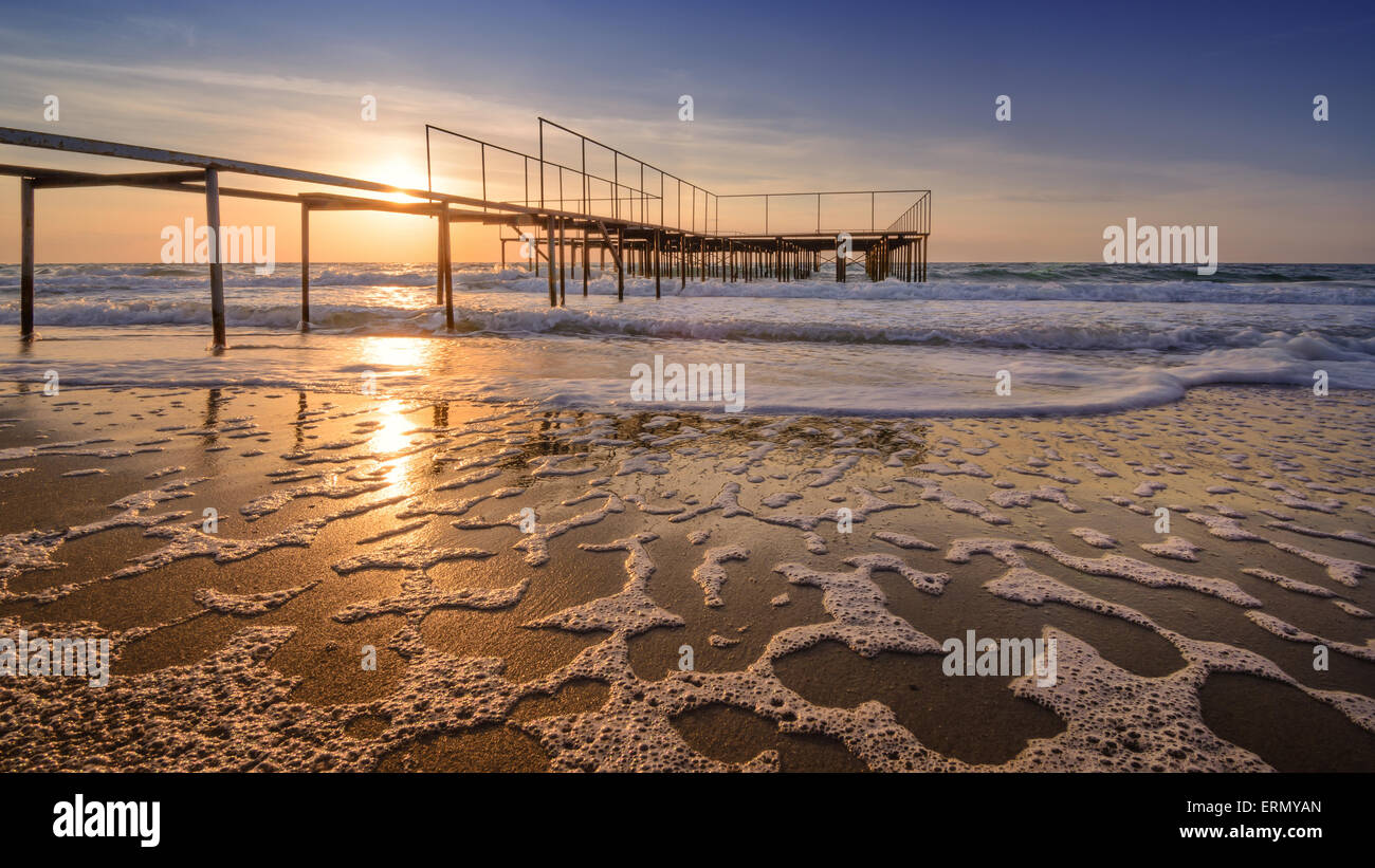 Alba sul vecchio molo oceano - onde del mare sullo sfondo insolito Foto Stock