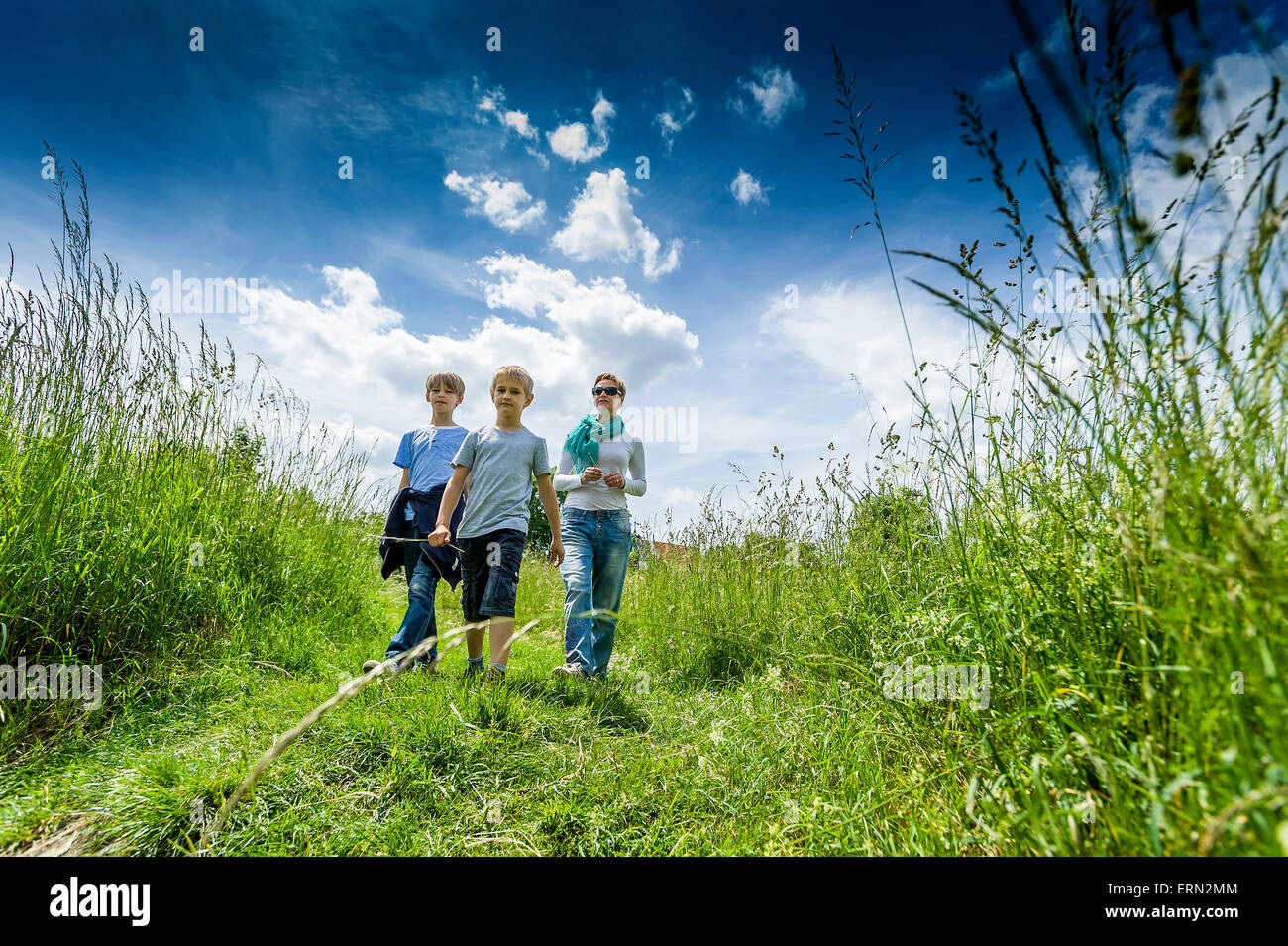 Due ragazzi di 9' e 11' in all'aperto a piedi con la loro madre Foto Stock