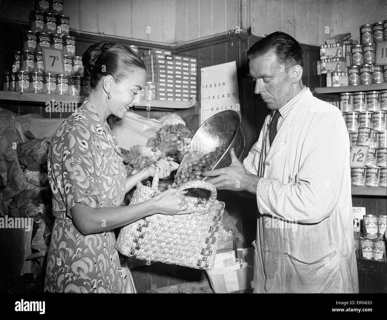 Una donna shopping in un negozio di fruttivendolo, 3 luglio 1950. Foto Stock