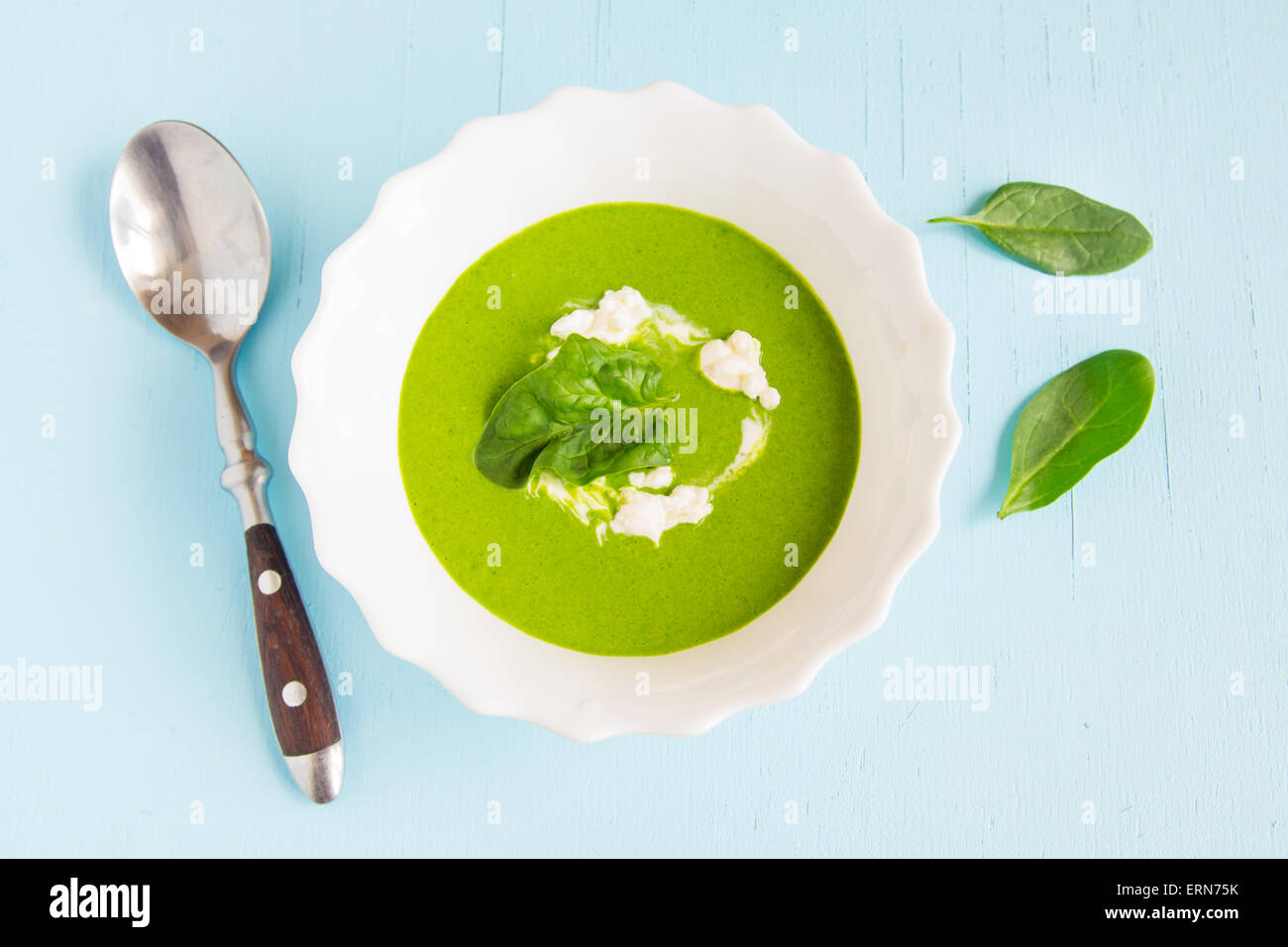 Verde di spinaci minestra in crema con panna acida su blu tavolo in legno Foto Stock