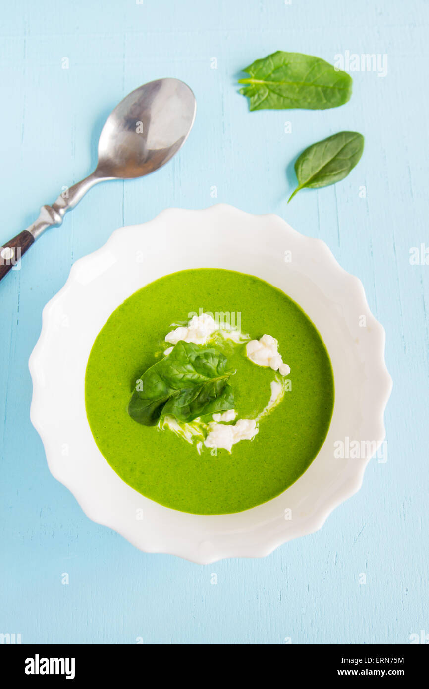 Verde di spinaci minestra in crema con panna acida su blu tavolo in legno Foto Stock