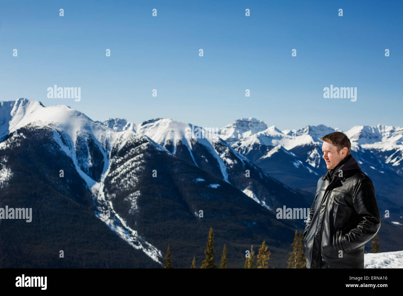 Sta un uomo con una vista dalla montagna di zolfo delle Canadian Rockies in inverno; Banff, Alberta, Canada Foto Stock