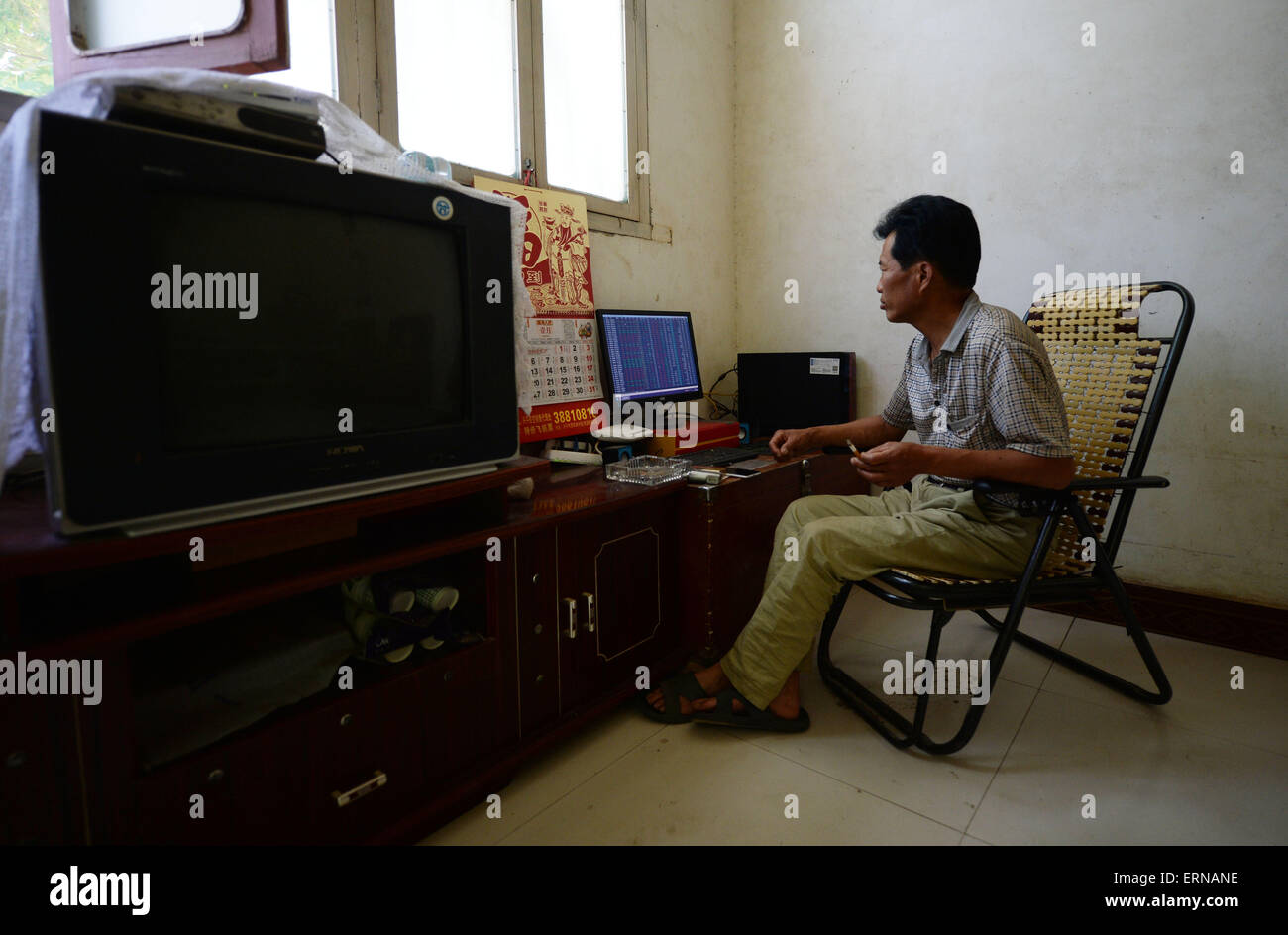 Xingping, la Cina della provincia di Shaanxi. 5 Giugno, 2015. Liu Qiming orologi stock linea di tendenza nella sua casa di villaggio Nanliu di Mawei township di Città Xingping, Cina nord-occidentale della provincia di Shaanxi, Giugno 5, 2015. Come il mercato azionario rally in Cina la maggior parte delle famiglie del villaggio Nanliu ha cominciato a investire in azioni. Essi mantengono un occhio sul loro valore magazzino quando il mercato è aperto ed eseguire lavori agricoli quando il mercato è chiuso. Credito: Liu Xiao/Xinhua/Alamy Live News Foto Stock