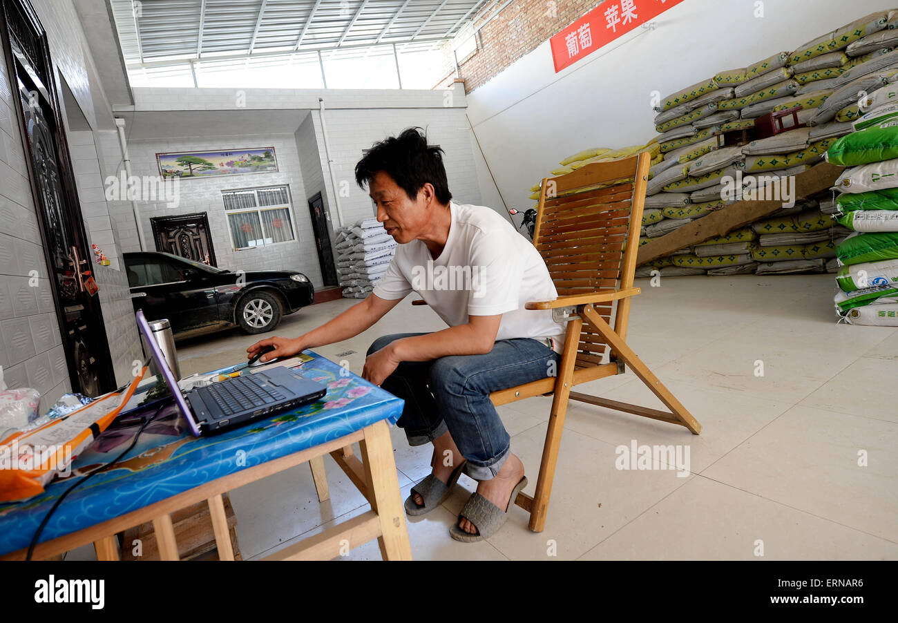 Xingping, la Cina della provincia di Shaanxi. 5 Giugno, 2015. Liu Lianguo orologi stock linea di tendenza a casa nel villaggio Nanliu di Mawei township di Città Xingping, Cina nord-occidentale della provincia di Shaanxi, Giugno 5, 2015. Come il mercato azionario rally in Cina la maggior parte delle famiglie del villaggio Nanliu ha cominciato a investire in azioni. Essi mantengono un occhio sul loro valore magazzino quando il mercato è aperto ed eseguire lavori agricoli quando il mercato è chiuso. Credito: Liu Xiao/Xinhua/Alamy Live News Foto Stock