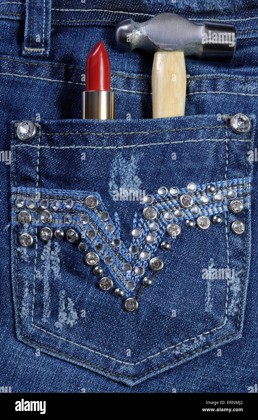 Lavoratore di sesso femminile che jeans blu con decorazione di strass e rossetto rosso e un martello in tasca posteriore per la creazione o la costruzione Foto Stock