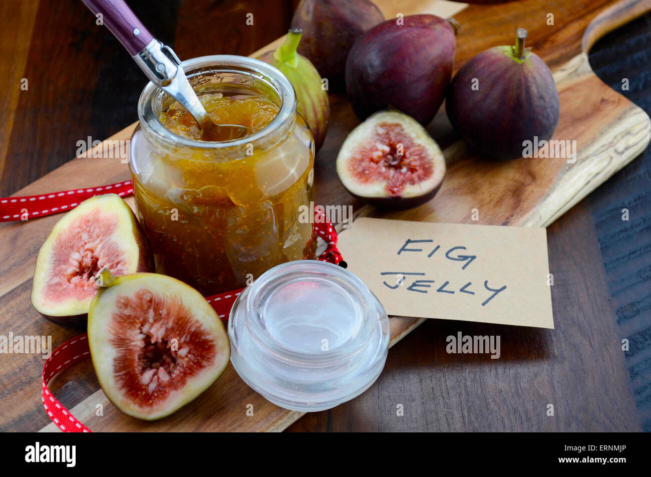 Fresche e mature frutto autunnale, fichi, con fig jelly preservare in vaso sul bordo di taglio contro il legno scuro dello sfondo. Foto Stock