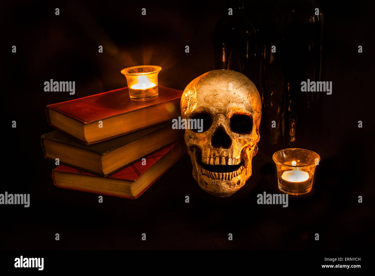 Un cranio vintage si siede accanto a una pila di vecchi romanzi e bottiglie di vino; immagine creata con una luce tecnica di pittura Foto Stock