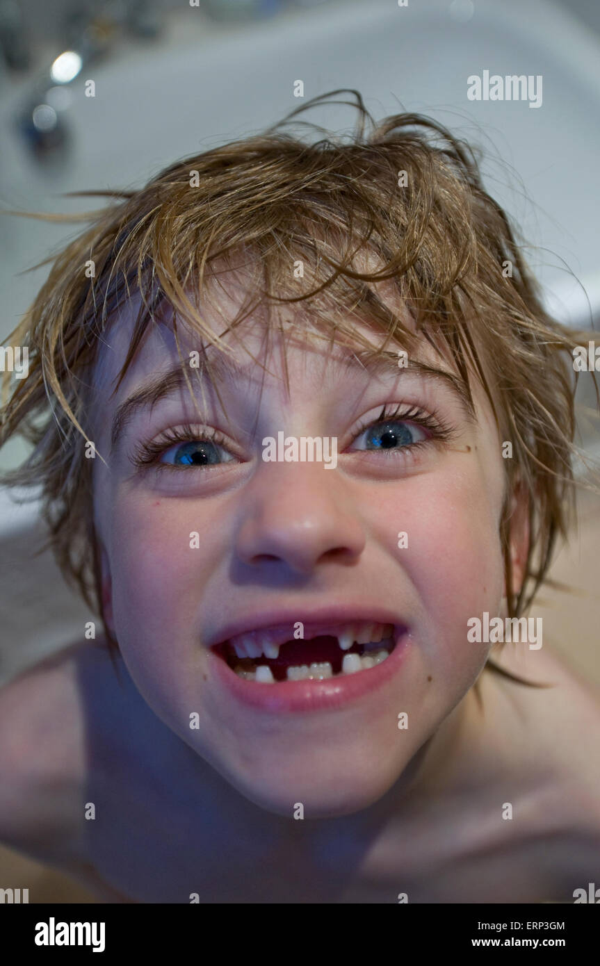 Un ragazzo con i capelli umidi e denti gappy sorrisi a fotocamera Foto Stock