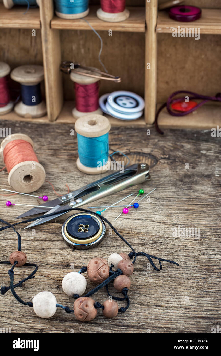 Perle,filo,i pulsanti artigiane su sfondo di legno.Il fuoco selettivo.Photo azzurrato Foto Stock