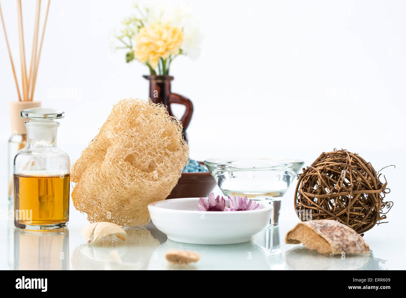 La cura del corpo con loofah, scrub, olio essenziale, spa, fiori galleggianti e candela Foto Stock