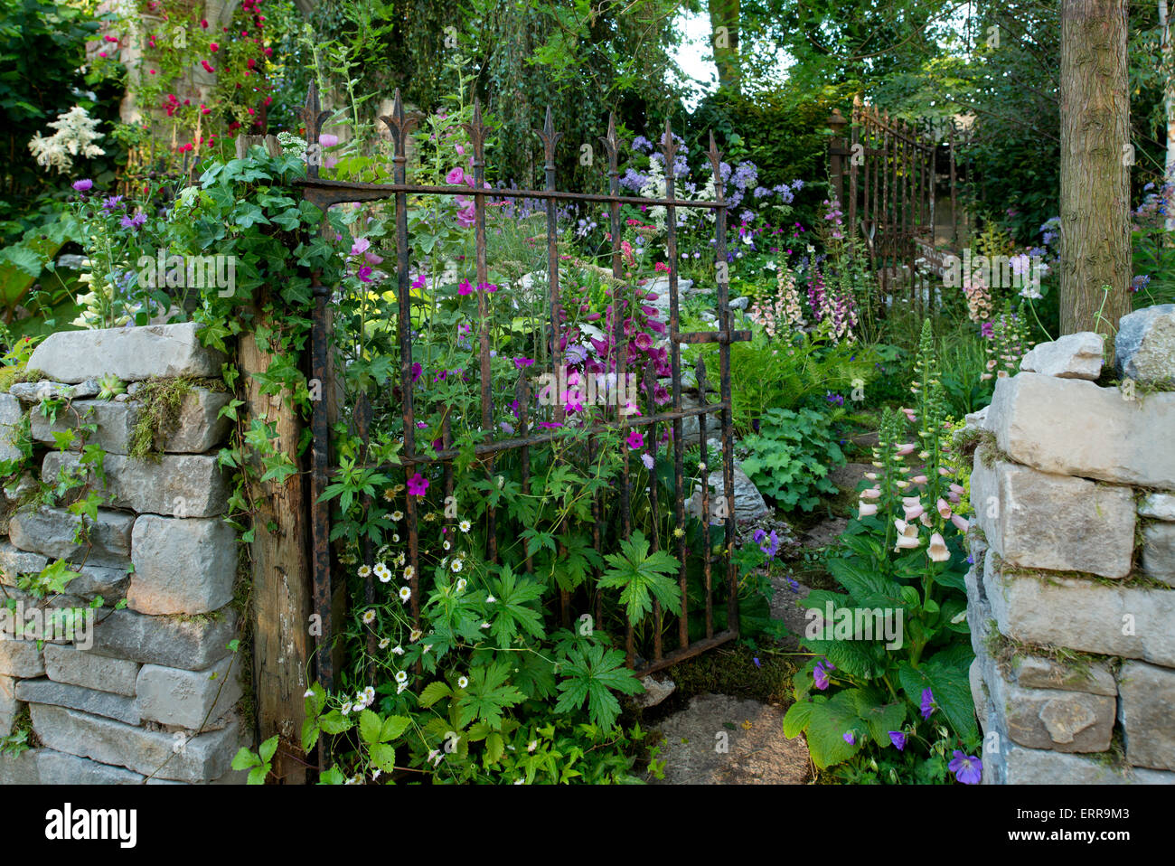 Un muro di pietra e porta di metallo che conduce nella dimenticata follia Giardino a Hampton Court Flower Show, 2014 Foto Stock