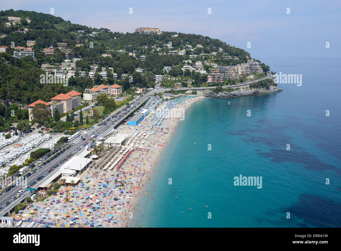 VISTA AEREA. Spiaggia affollata nella città di Bergeggi. Provincia di Savona, Liguria, Italia. Foto Stock