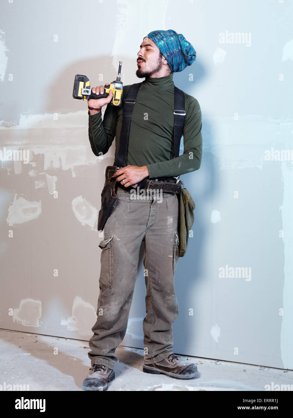 Ironico ritratto dell uomo lavoratore contraente soffiando a pistola a vite Foto Stock