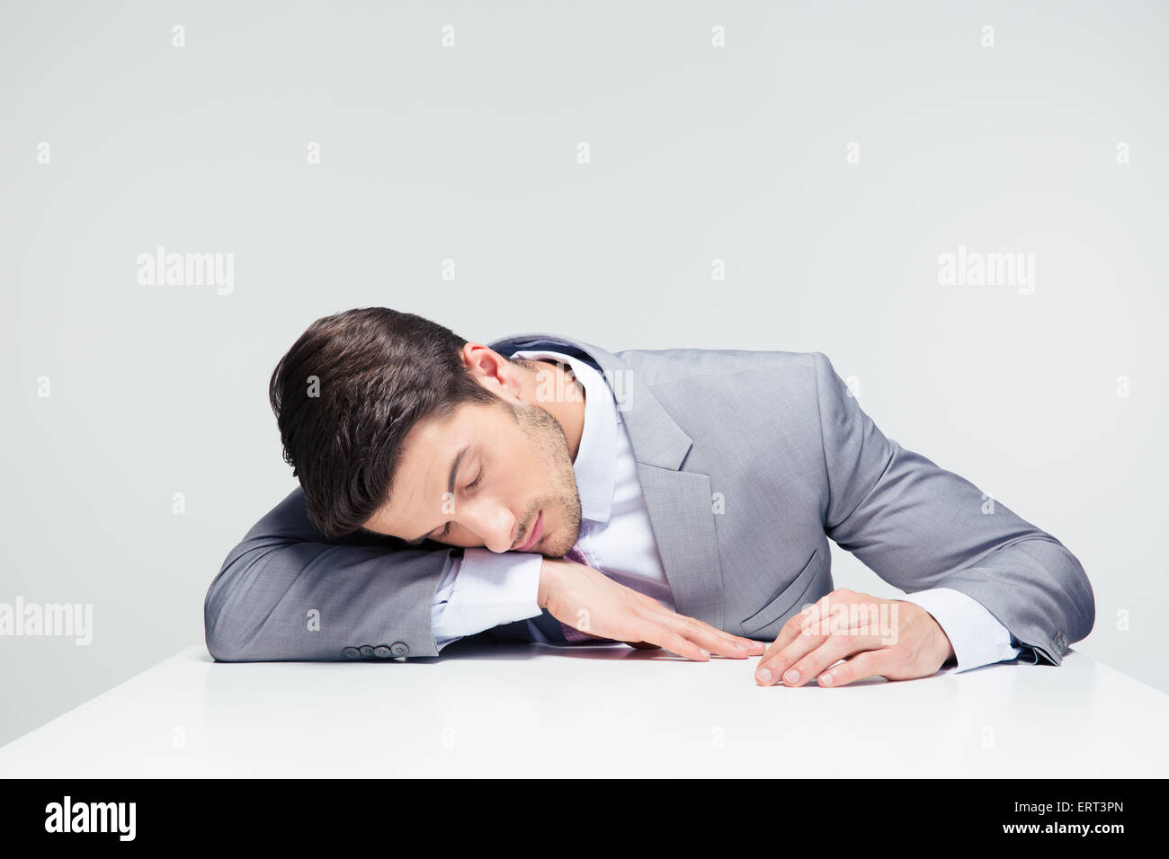 Imprenditore dormire sul tavolo su sfondo grigio Foto stock - Alamy