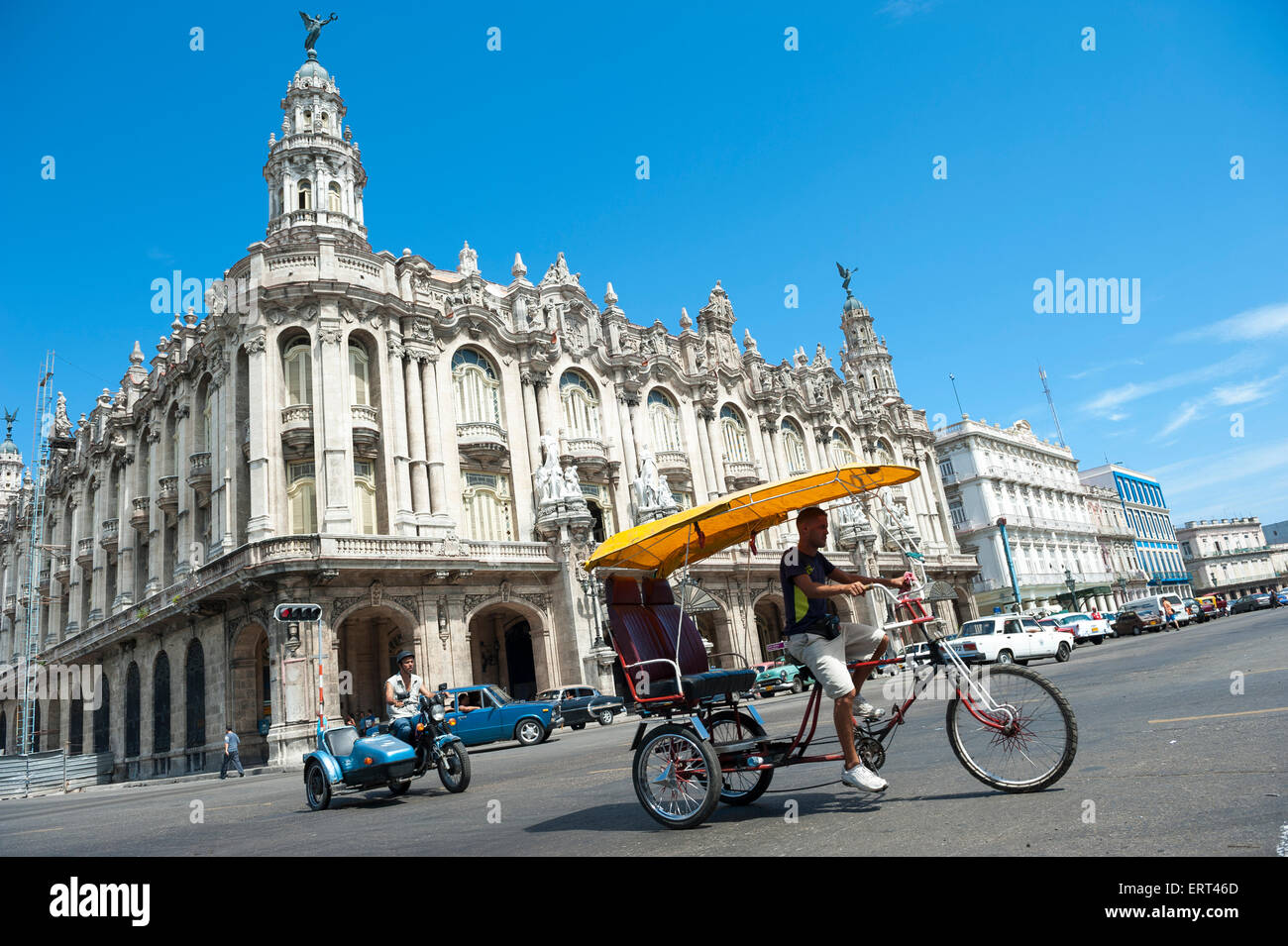 L'Avana, Cuba - Giugno, 2011: taxi bicicletta noto localmente come un bicitaxi pedali passato il punto di riferimento del teatro grande edificio. Foto Stock