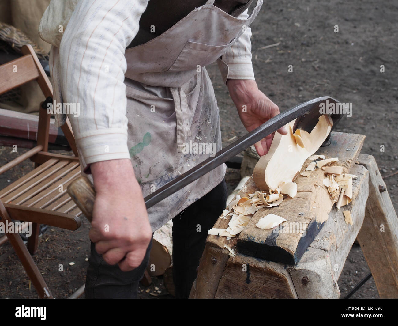 L'uomo dimostrando l'uso di un tradizionale strumento di taglio per rendere scarpe di legno Foto Stock