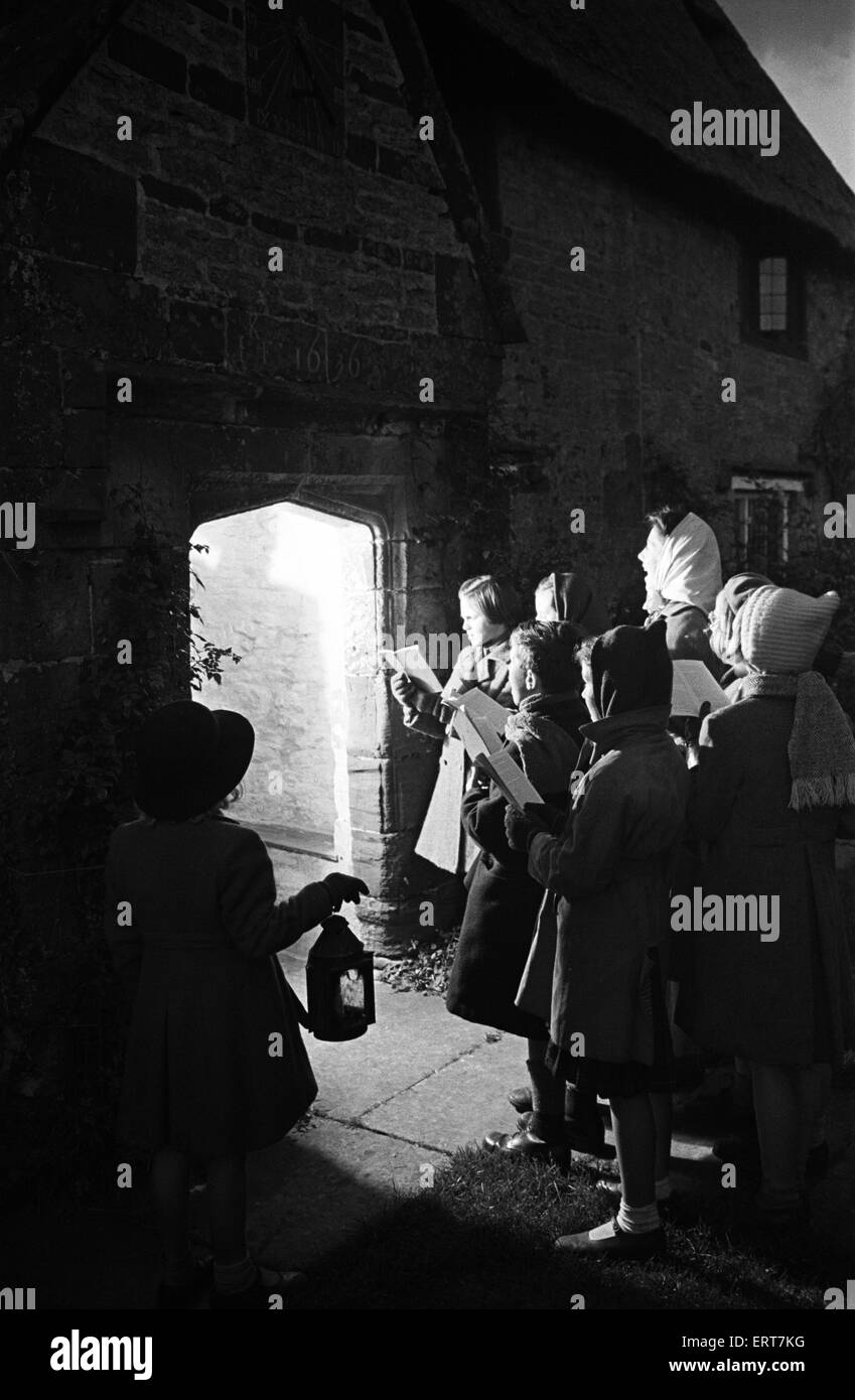 Adulti e bambini canti di natale di notte tempo fuori Sulgrave Manor, Northamptonshire. Sulgrave Manor è ben noto per essere la casa degli antenati di George Washington, circa 1945. Foto Stock