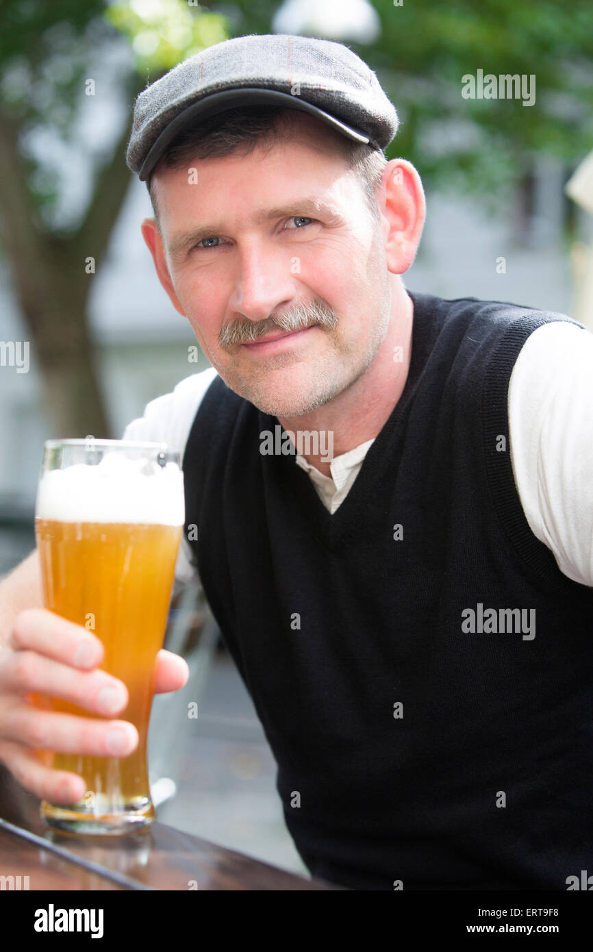 Uomo seduto fuori con un bicchiere di birra Foto Stock