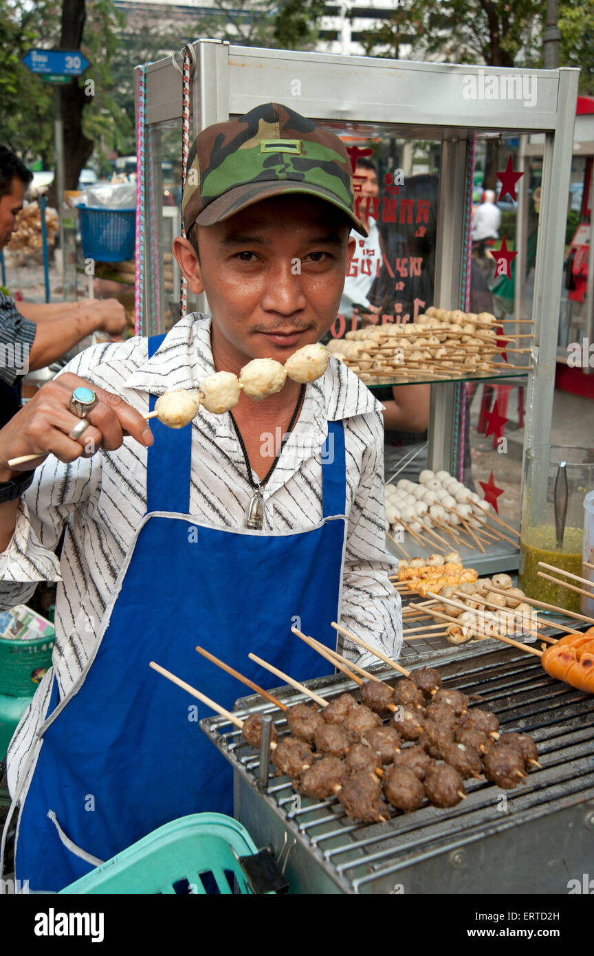 Bangkok tradizionale polpetta venditore regge uno spiedino di polpette di carne al suo polpetta stallo grill Bangkok in Thailandia Foto Stock