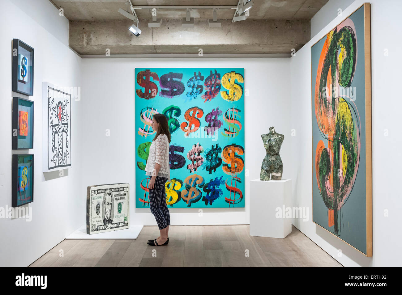 Londra, Regno Unito. 8 Giugno, 2015. Un Sotheby's membro dello staff si erge tra (l a r) "tre segni di dollaro' da Andy Warhol, "Untitled" da Keith Haring, '50 dollari' da Jin Wang, 'Dollaro' segni di Andy Warhol, "Venus aux dollari' di Arman e 'Dollaro' segno di Andy Warhol, in anteprima di 'al portatore on demand", una collezione privata di 21 opere ispirate dal dollaro, tra cui Andy Warhol capolavori che saranno vendute all'asta il 1 e 2 luglio. La raccolta è stimato per realizzare € 50 milioni. Credito: Stephen Chung/Alamy Live News Foto Stock