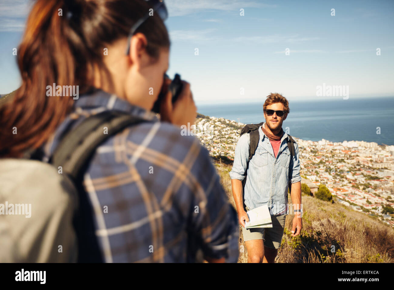 Giovane uomo in posa nella natura, con la donna che parla della sua foto in campagna in un giorno di estate durante le escursioni. Giovane donna prendendo phot Foto Stock