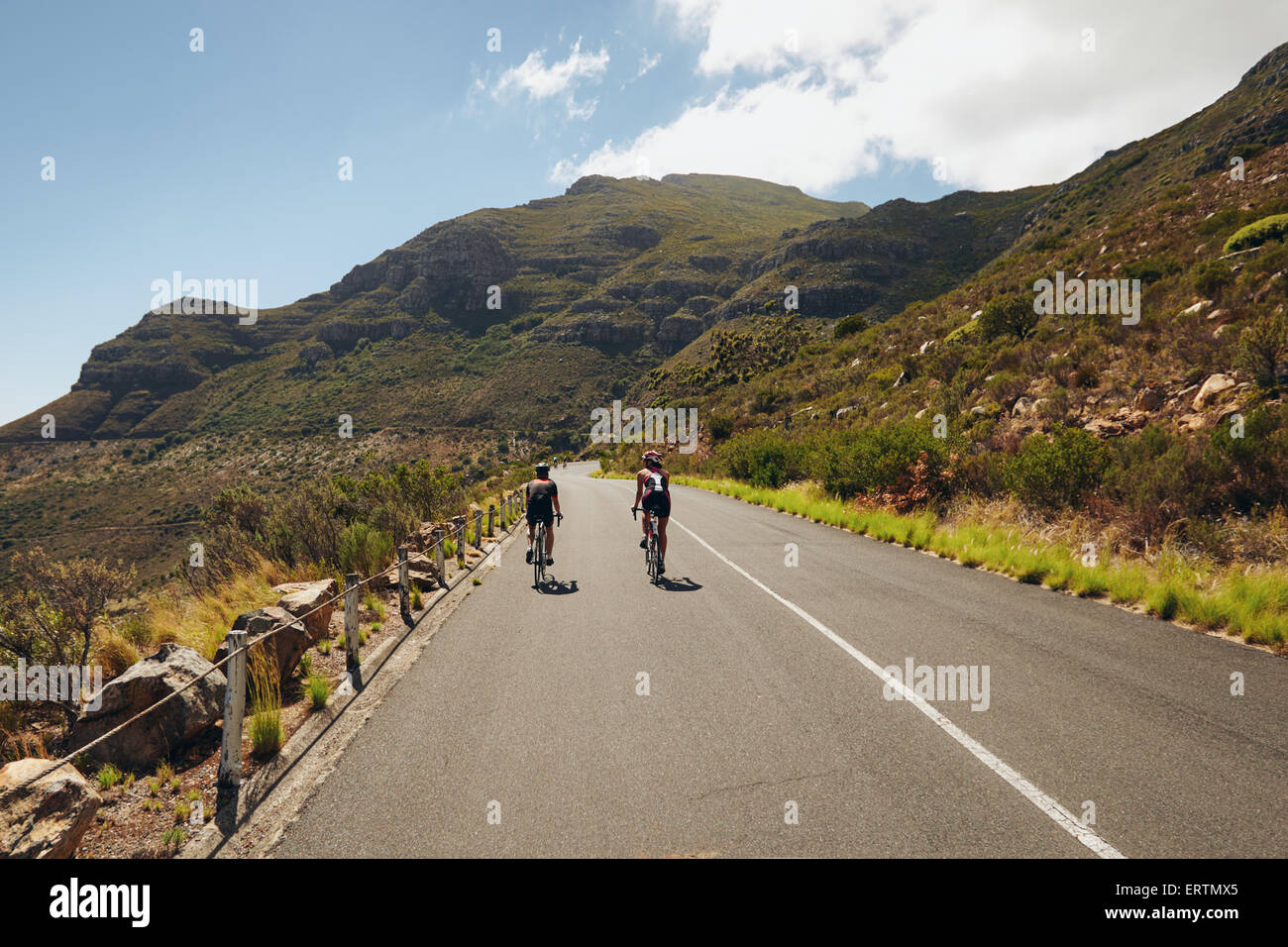 Vista posteriore di due ciclista cavalcare giù per il paese la strada attraverso le montagne. Manifestazione ciclistica di triathlon. Triatleti pra Foto Stock