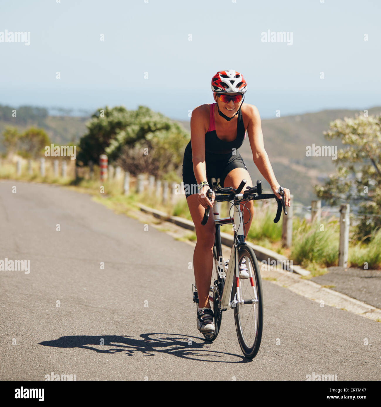 Donna triathlon atleta ciclista in discesa sulla strada di campagna. Giovane donna Bicicletta Equitazione su strada aperta, la pratica per il triathlon com Foto Stock