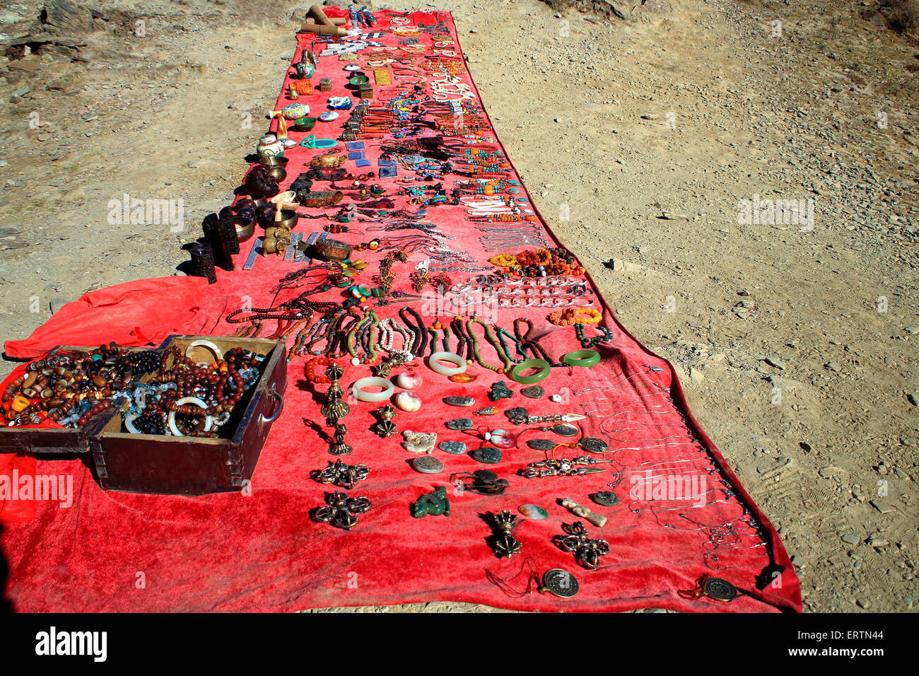 Pressione di stallo di Souvenir visualizzati su stoffa rossa sul terreno la vendita di artigianato tibetano-minuterie di fantasia a metà strada fino a Kamba La-Tibet Foto Stock