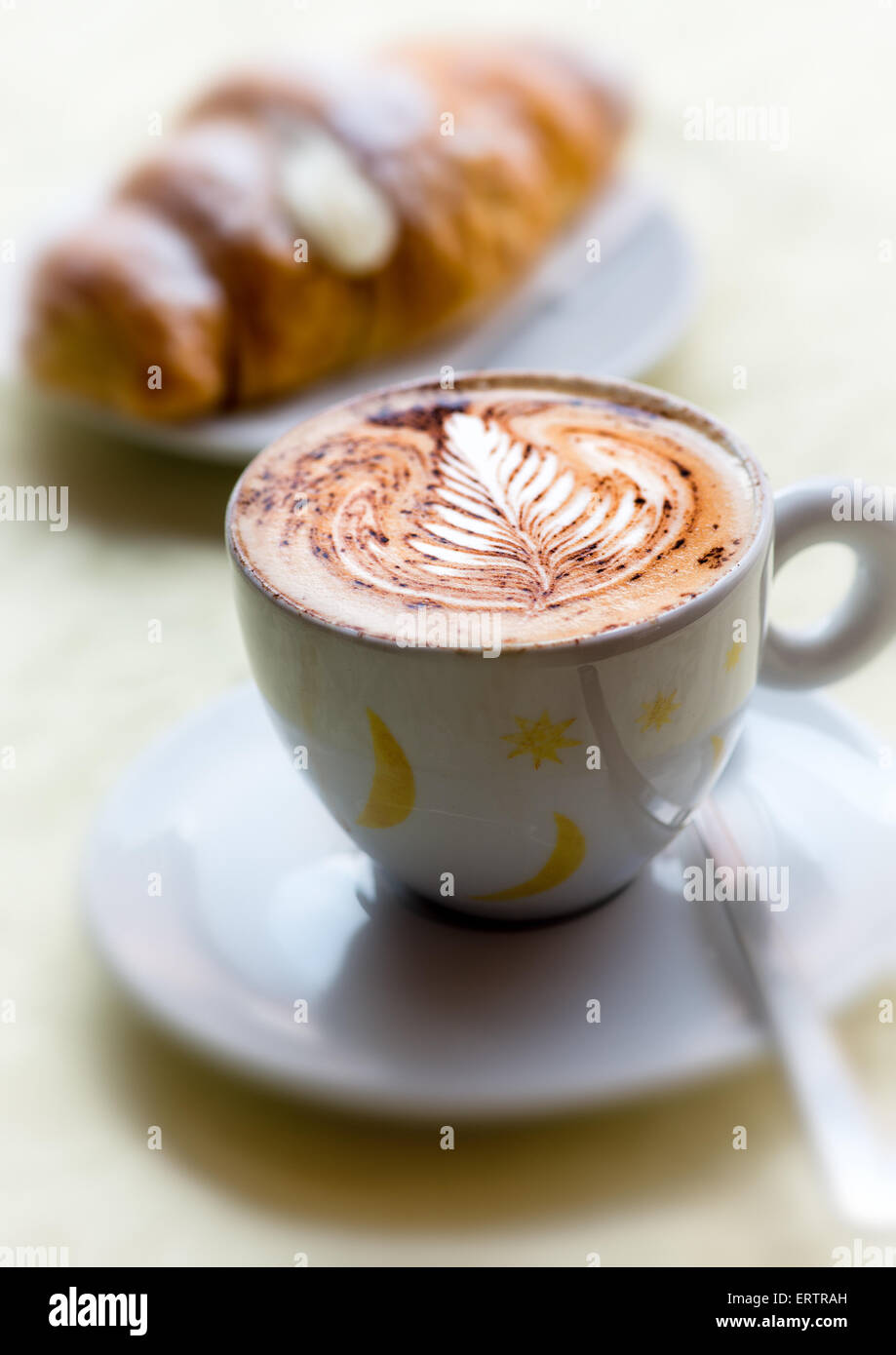 Coppa decorativa del preparato di fresco cappuccino caldo con una foglia pattern nella spuma lattiginosa servita con una brioche Foto Stock