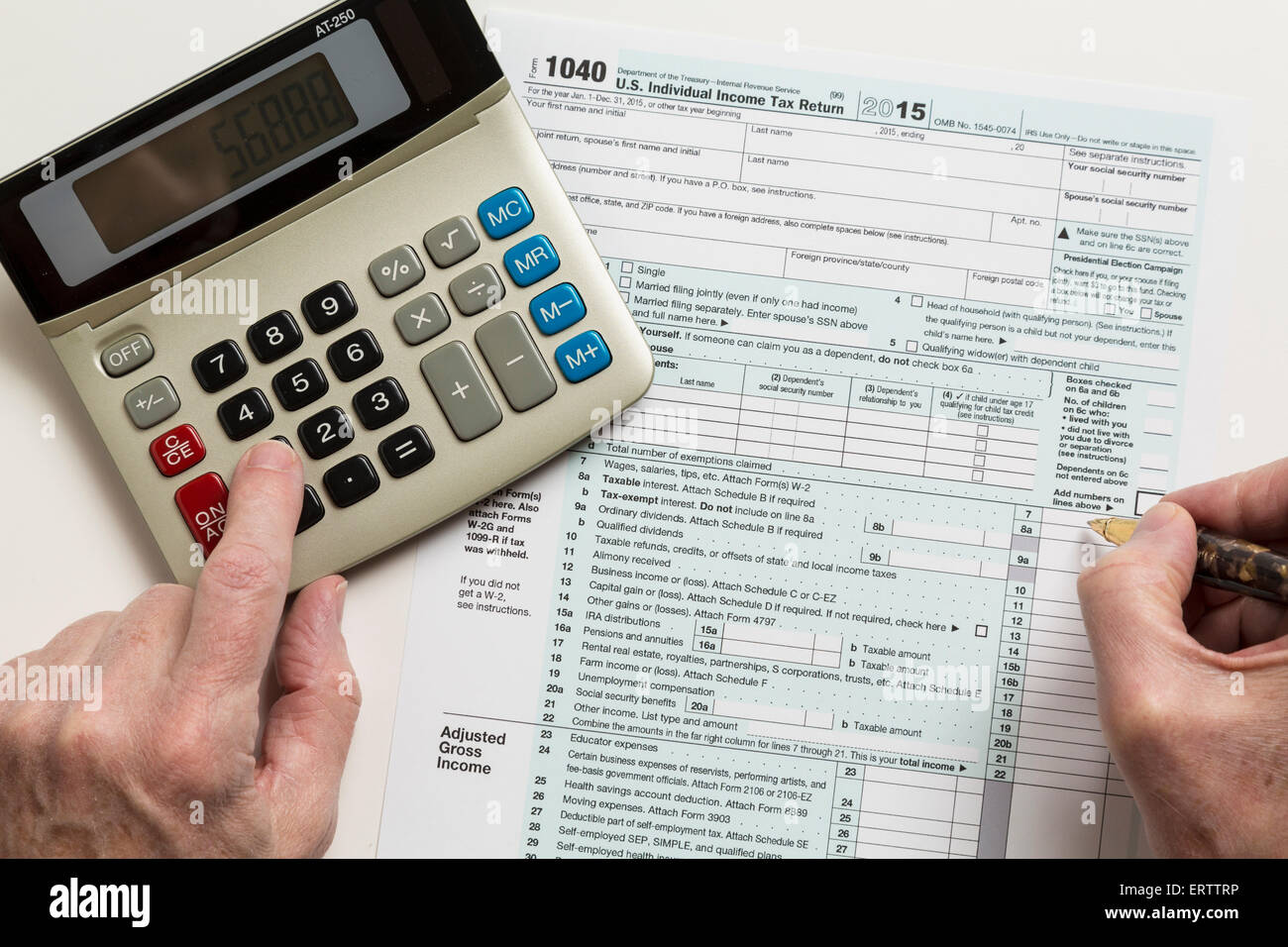 L'uomo il riempimento in USA sotto forma di imposta 1040 per l'anno 2015 con la calcolatrice Foto Stock