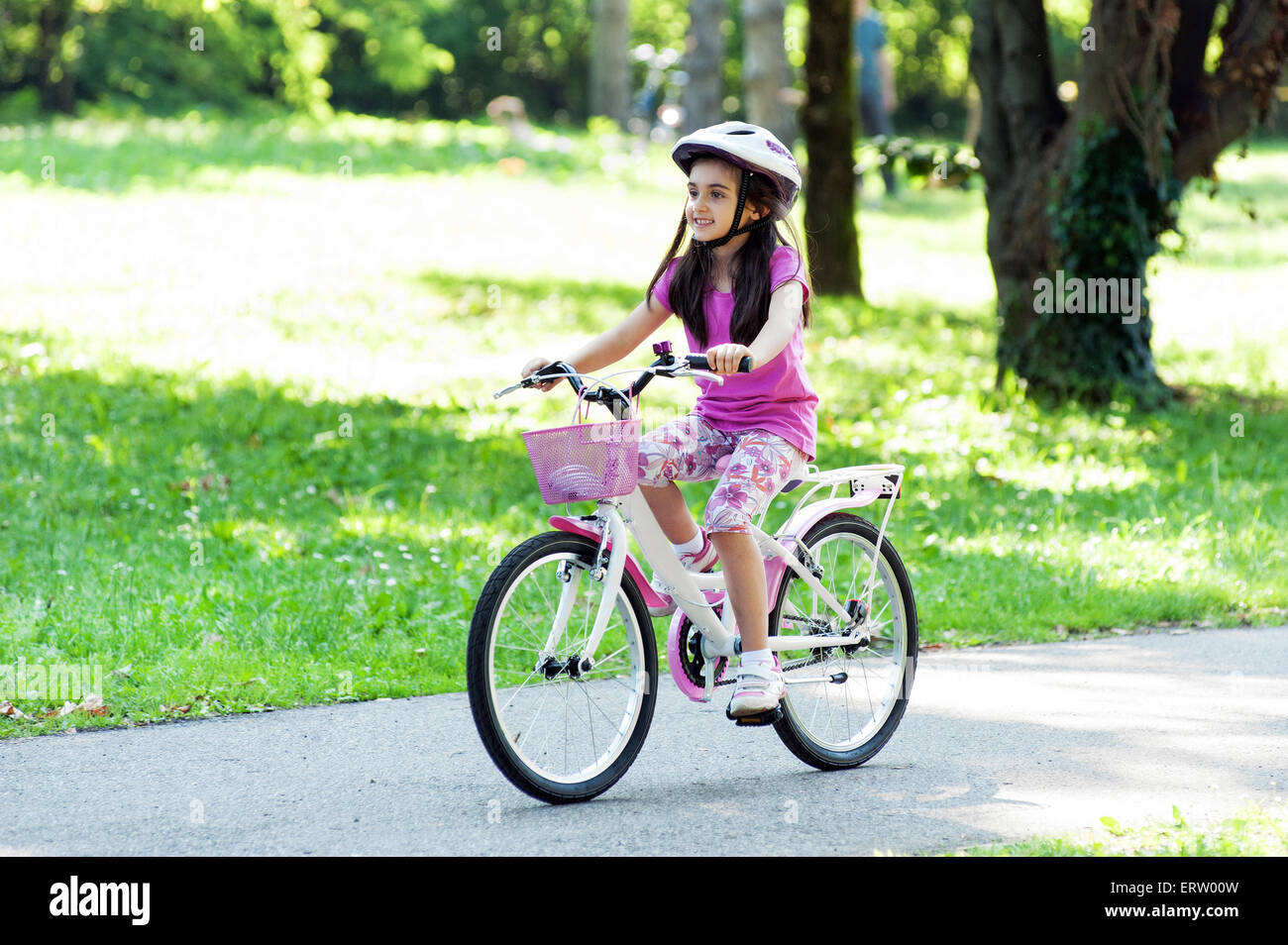Bambina in un quartiere alla moda di abito rosa con abbinamento di rosa mountain bike e casco in sella la sua bicicletta Foto Stock
