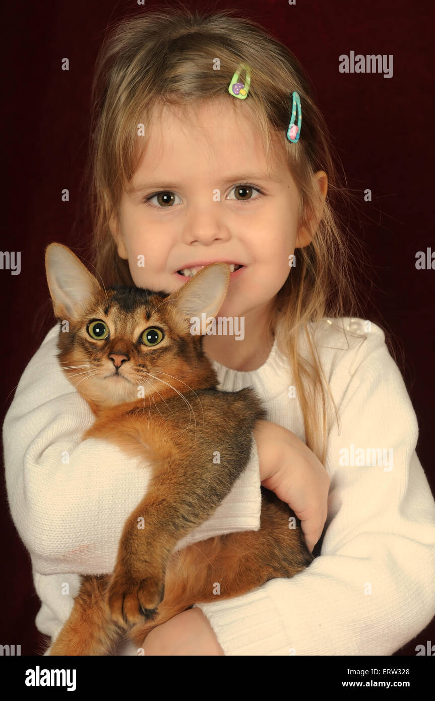 Pretty girl cinque anni con la razza somala gattino Ruddy colore sia guardando la telecamera, ragazza sorride Foto Stock