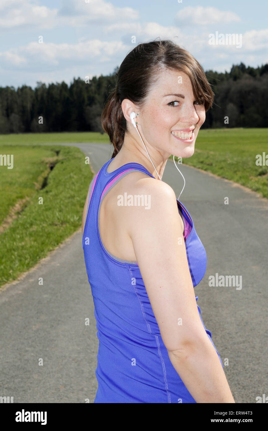 Giovane donna all'aperto in allenamento vestiti con le cuffie Foto Stock