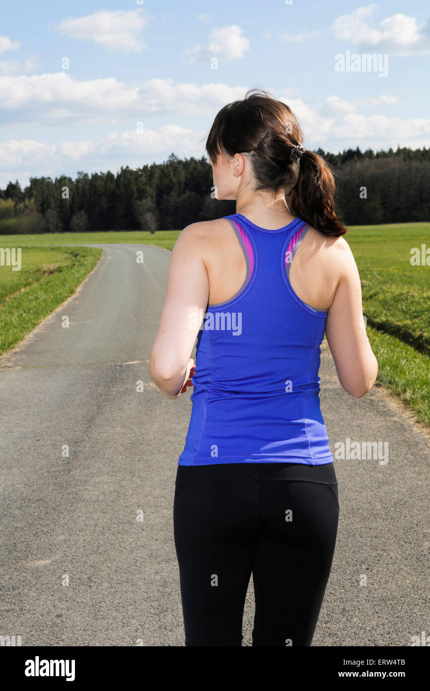 Retro di una giovane donna jogging all'aperto sulla campagna Foto Stock