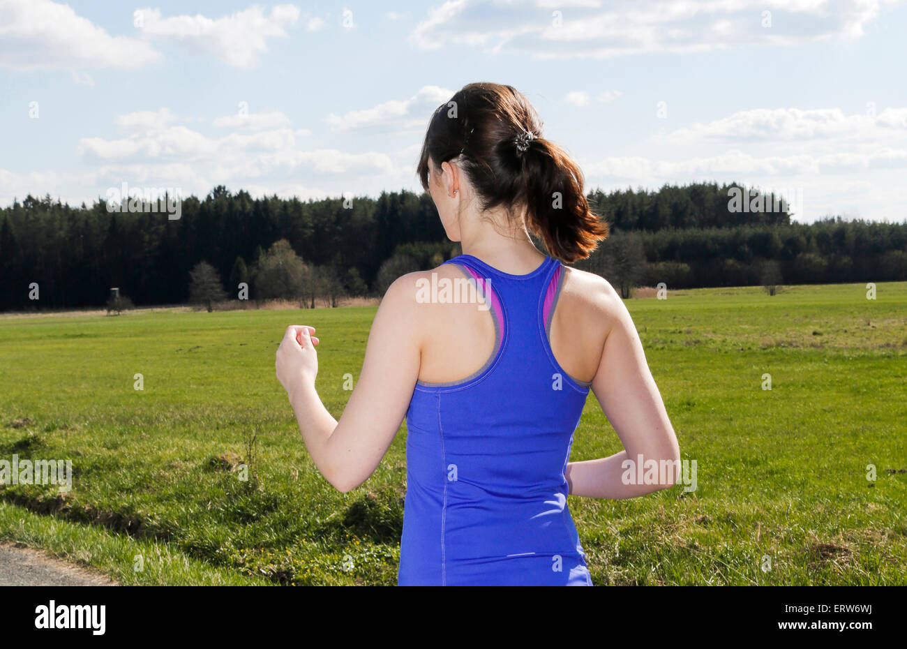 Retro di una giovane donna jogging all'aperto sulla campagna Foto Stock