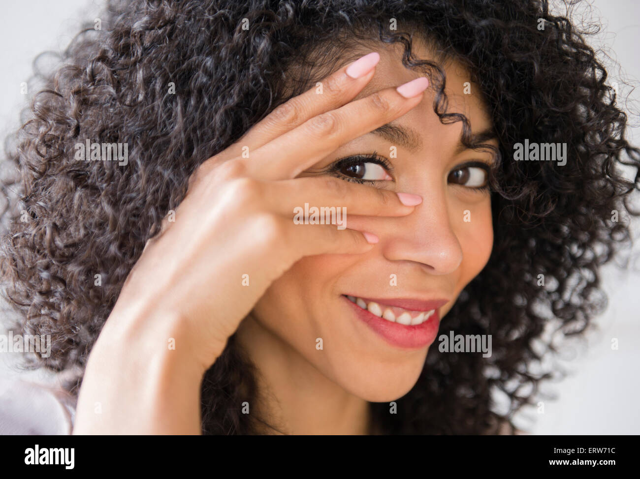 Razza mista donna con capelli ricci sorridente Foto Stock