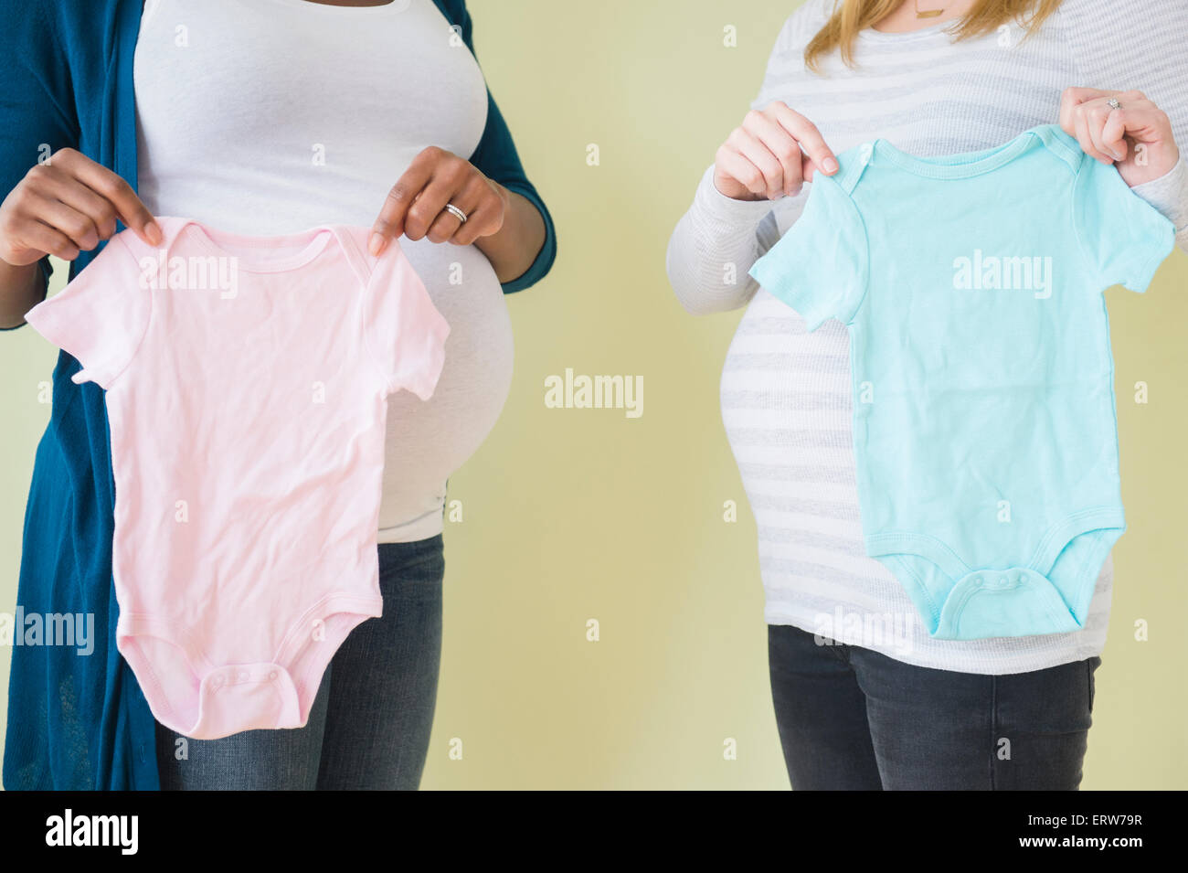 Donne in stato di gravidanza tenendo un ragazzo e una ragazza vestiti del bambino Foto Stock