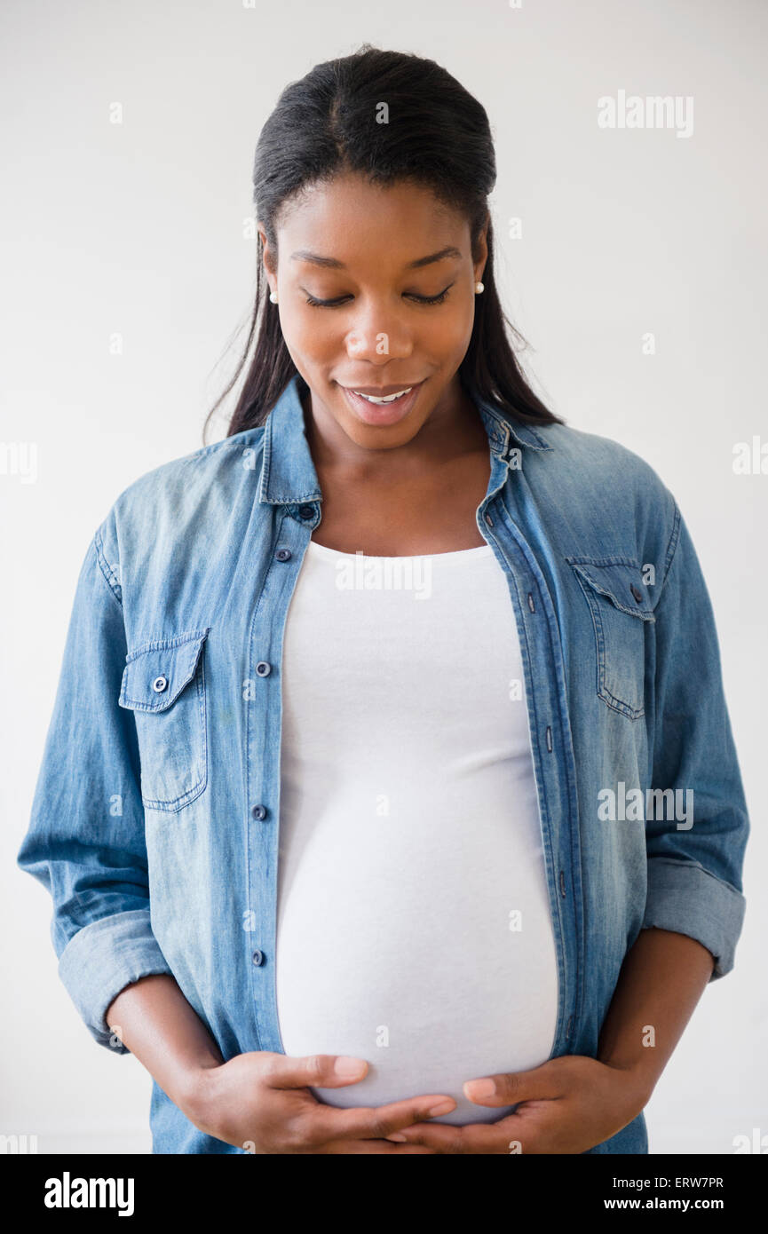 Nero donna incinta ammirando il suo stomaco Foto Stock