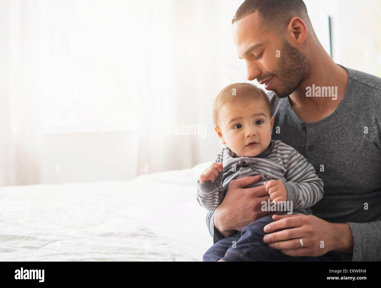 Padre sorridente holding baby figlio sul letto Foto Stock