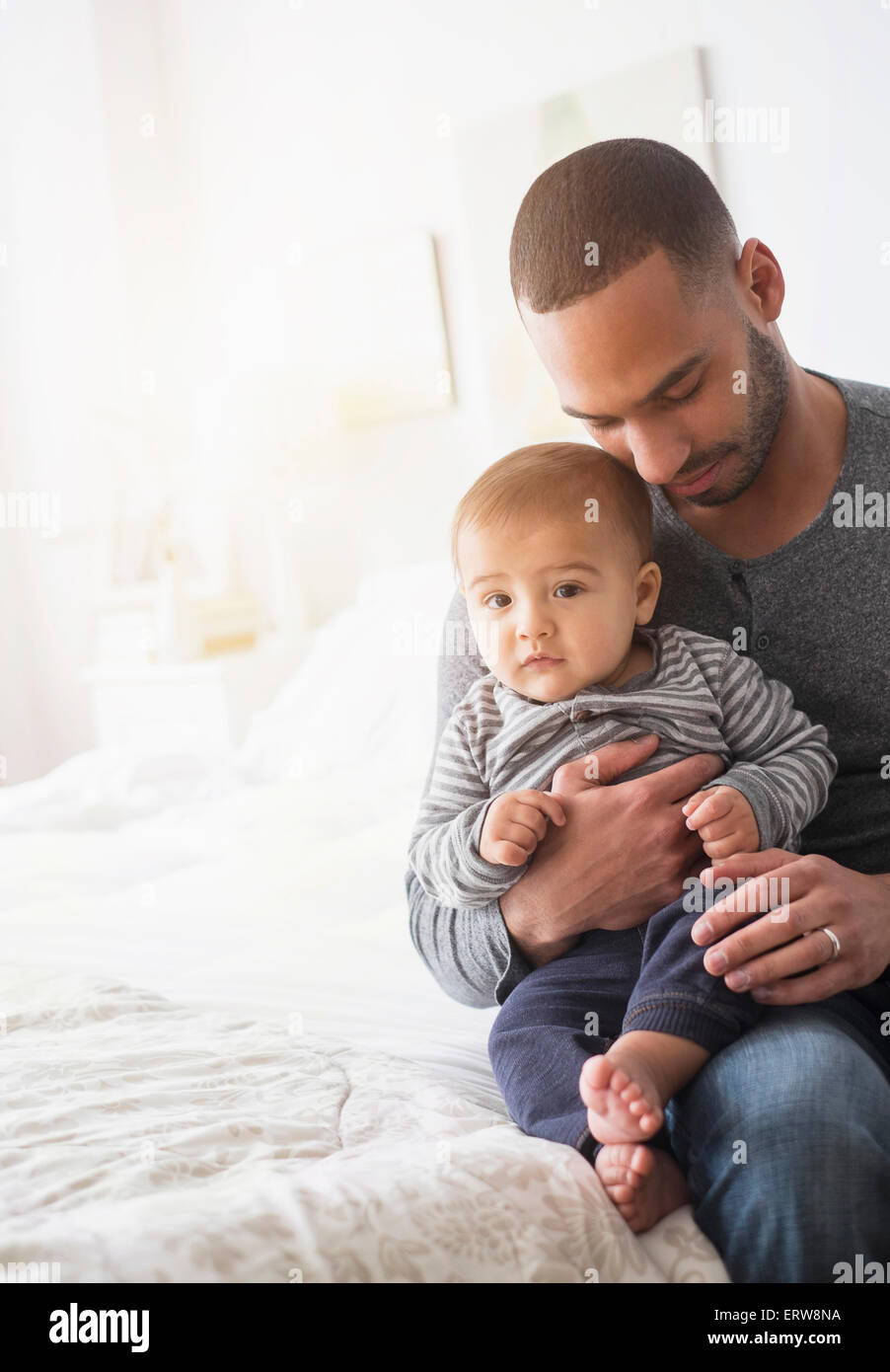 Padre sorridente holding baby figlio sul letto Foto Stock