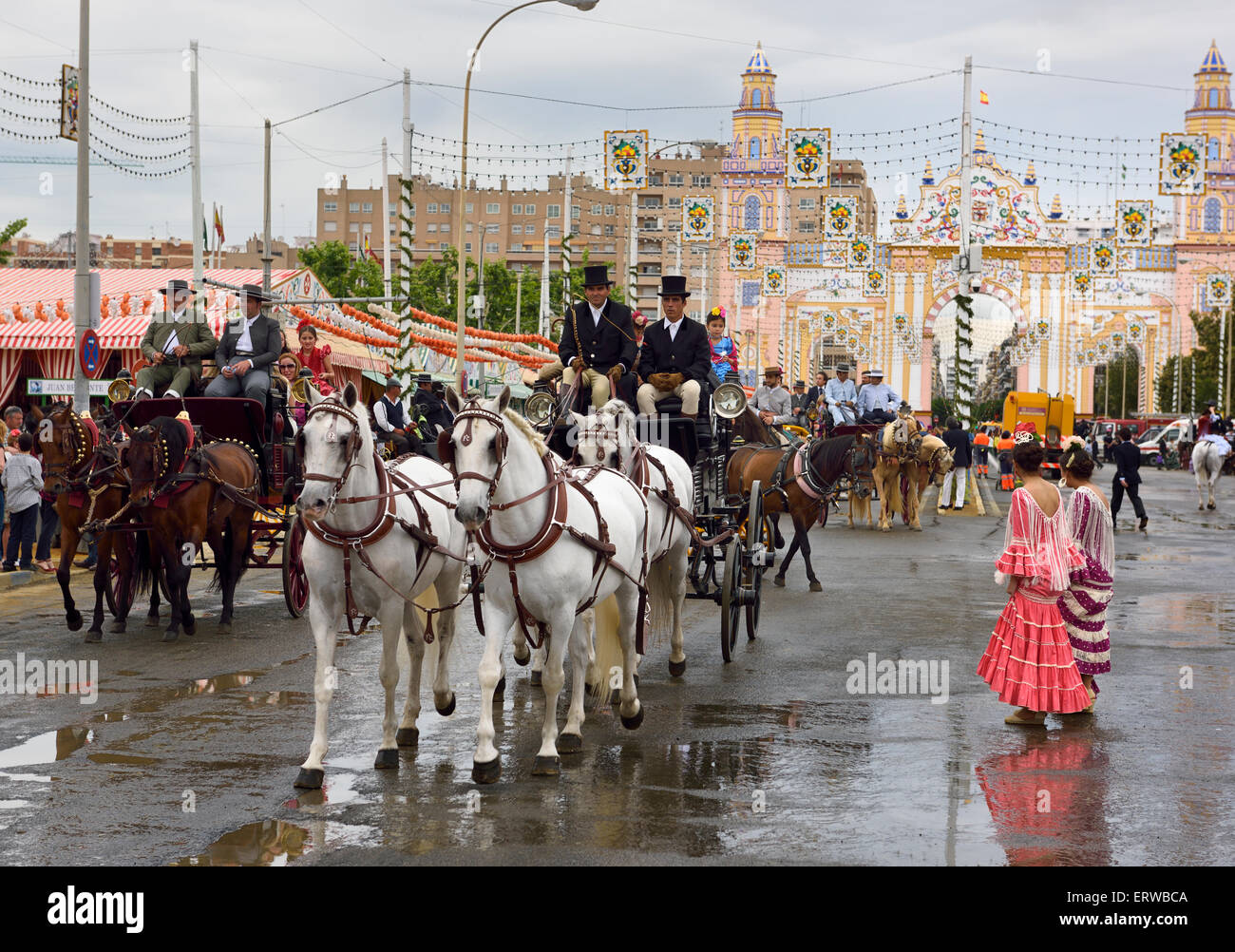 Il team di cavallo tirando i carrelli con le famiglie su lavato street presso il cancello principale 2015 Siviglia fiera di aprile Foto Stock