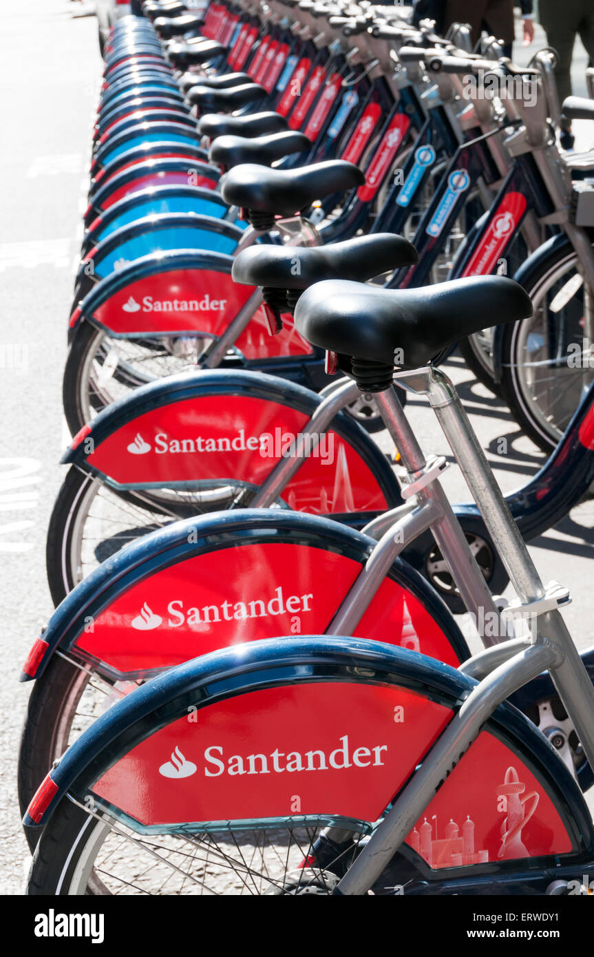 Sponsorizzazione di Santander su una fila di 'Boris delle bici a noleggio in Londra, con alcuni vecchi Barclays sponsorizzato biciclette in background. Foto Stock