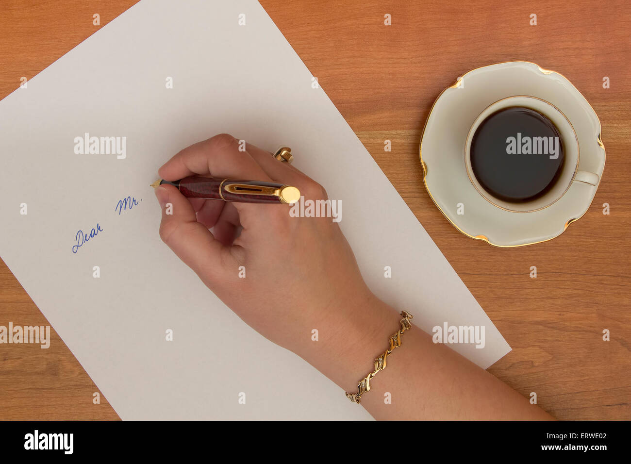 Femmina scrittura a mano lettera su bianco della carta da ufficio sulla scrivania in legno. Foto Stock