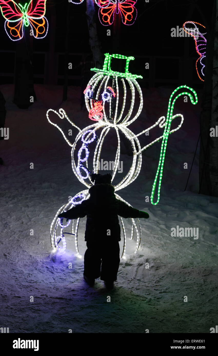 Il profilarsi di un bambino guardando un pupazzo di neve fatta di luci come parte di FestiLumiere nella città di Québec il Winter Carnival Foto Stock