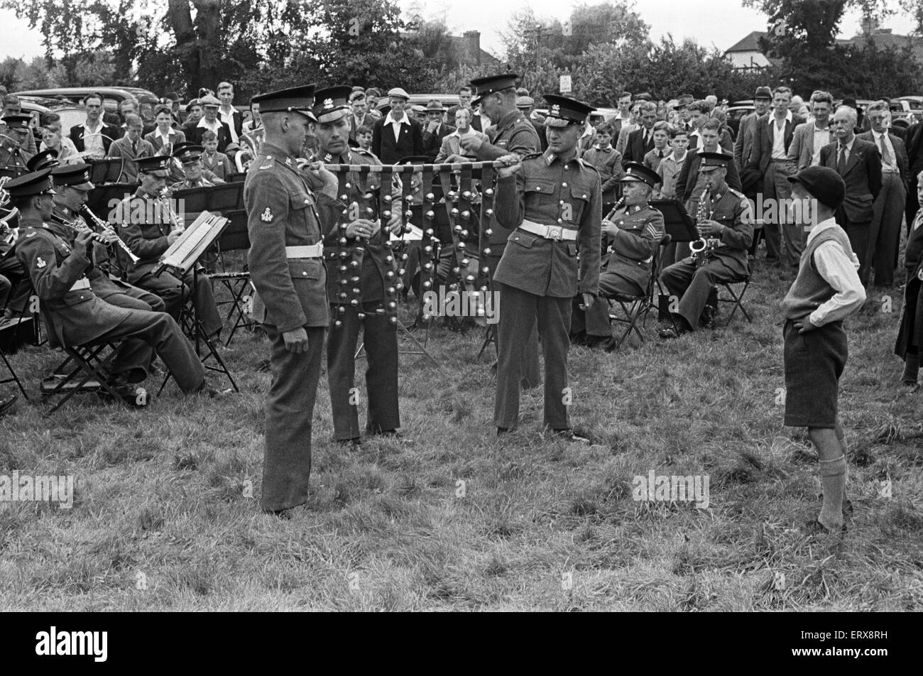 Un giovane ragazzo guardando una banda militare la riproduzione durante la settimana di Canterbury Kent. Nel centro sono tre gli uomini che giocano la slitta campane. Agosto 1947. Foto Stock