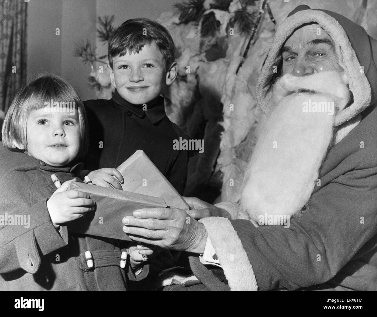 Un rapido avvio di Natale per Clare Bartlem, di età compresa tra i tre e i suoi sei anni fratello, Gerald, da Chester, in quanto ricevono regali da Babbo Natale al San Francesco Christmas Bazaar. Il 30 ottobre 1965 Foto Stock