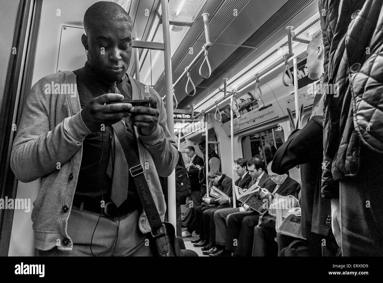 Uomo nero utilizzando il suo telefono cellulare su una metropolitana. Foto Stock