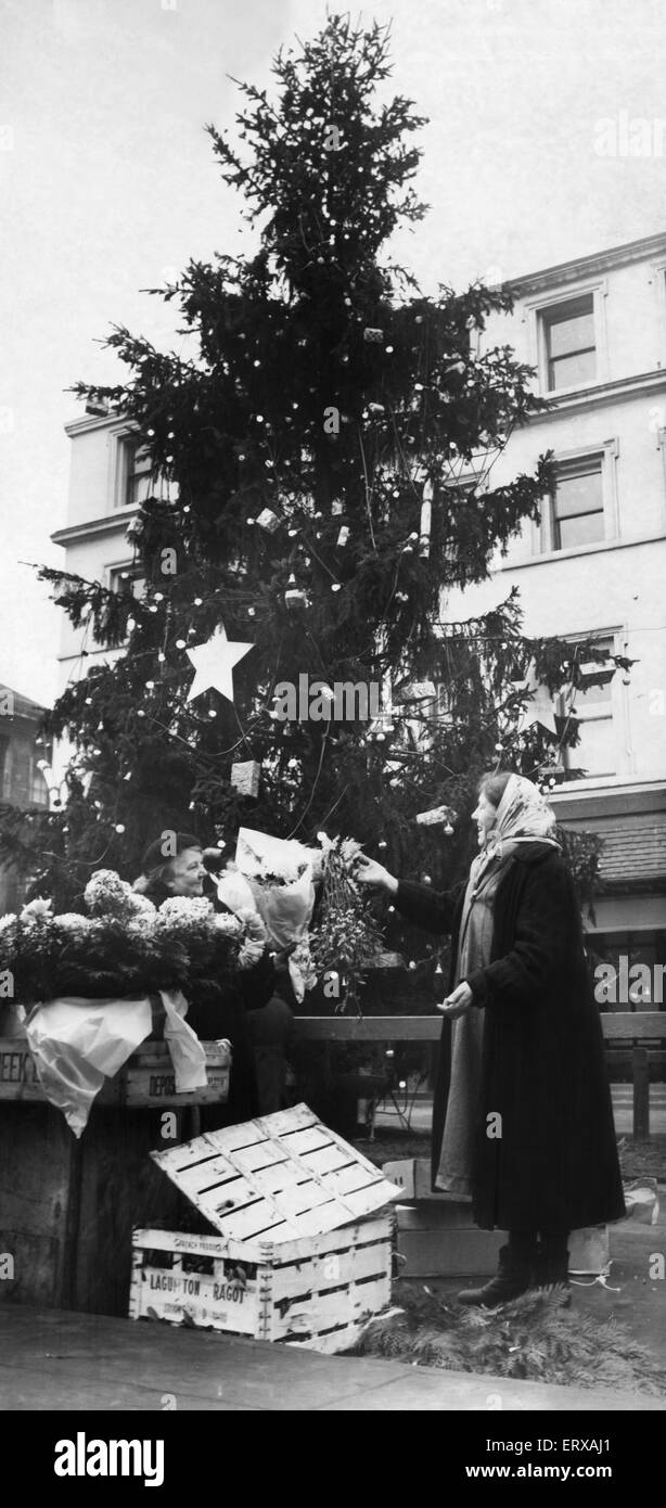 Liverpool venditori di fiori ha fatto un vivace commercio di vendita di vischio e agrifoglio intorno alla Civic albero di Natale a Clayton Square. 24 Dicembre 1955 Foto Stock